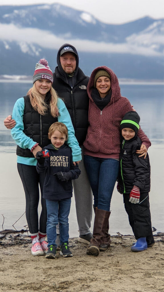 a family of 4 standing in front of a mountain.