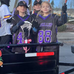 Two lacrosse players in a trailer during a parade.