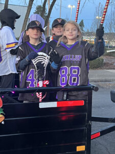 Two lacrosse players in a trailer during a parade.