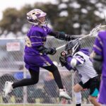 A lacrosse player jumping and shooting