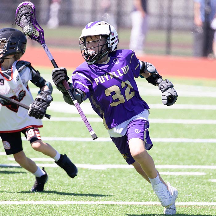 A lacrosse player running with a lacrosse stick.