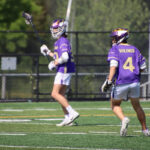 Two lacrosse players in purple jerseys.