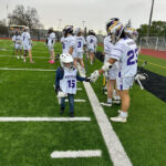 A kindergarten lacrosse player giving high five to a high school player.