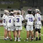 A group of lacrosse players in white jerseys.